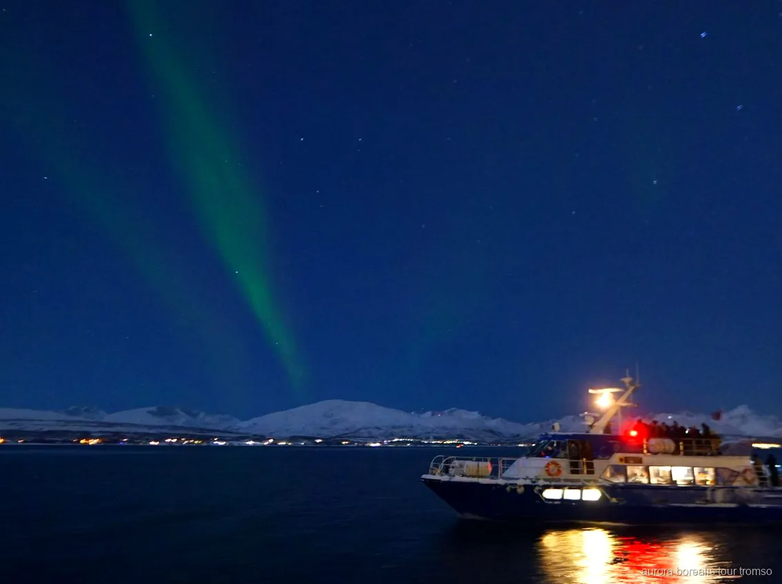 Northern Lights over the fjord seen from the Tromso aurora cruise boat