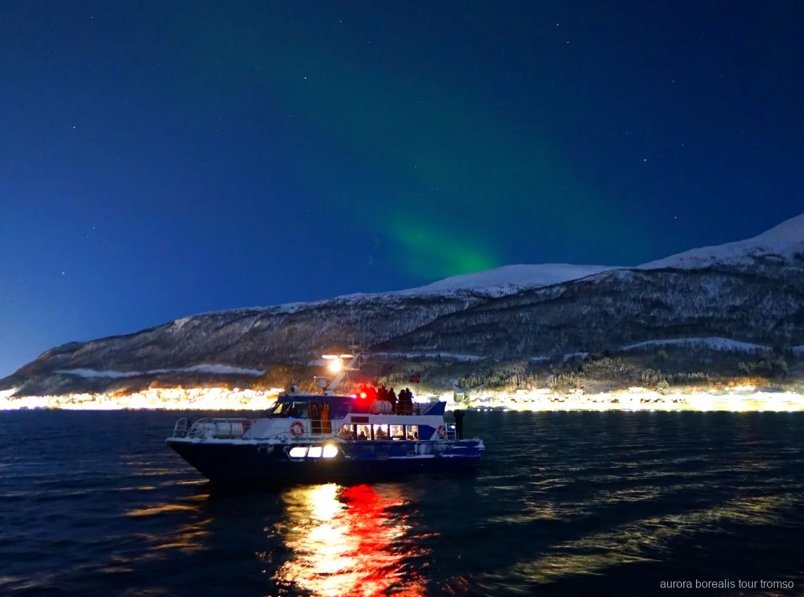 Crew member helping a guest with camera settings on the Tromso aurora cruise